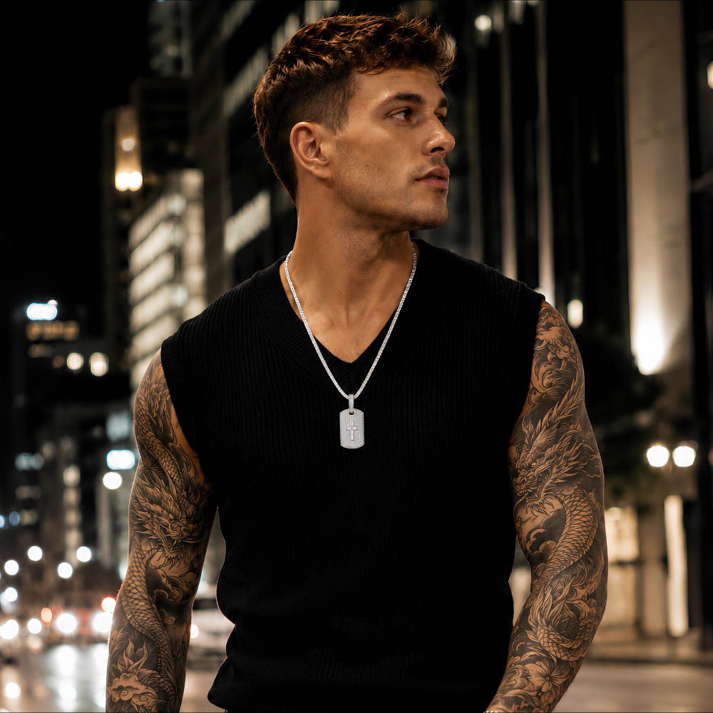 Man with tattoos standing in an urban setting at night wearing moissanite pendant in S925 sterling silver with platinum finish featuring integrated cross form