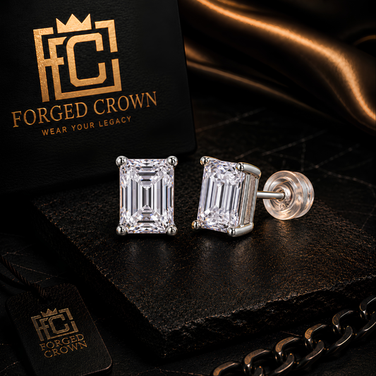 Moissanite stud earrings in S925 sterling silver with platinum finish, emerald cut stones displayed on black stone slab with Forged Crown branding