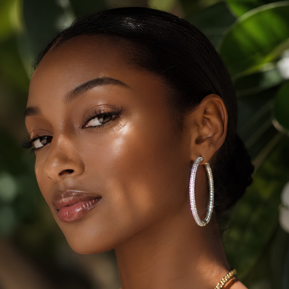 Woman wearing large silver moissanite hoop earrings with continuous pave setting in front of a blurred green background
